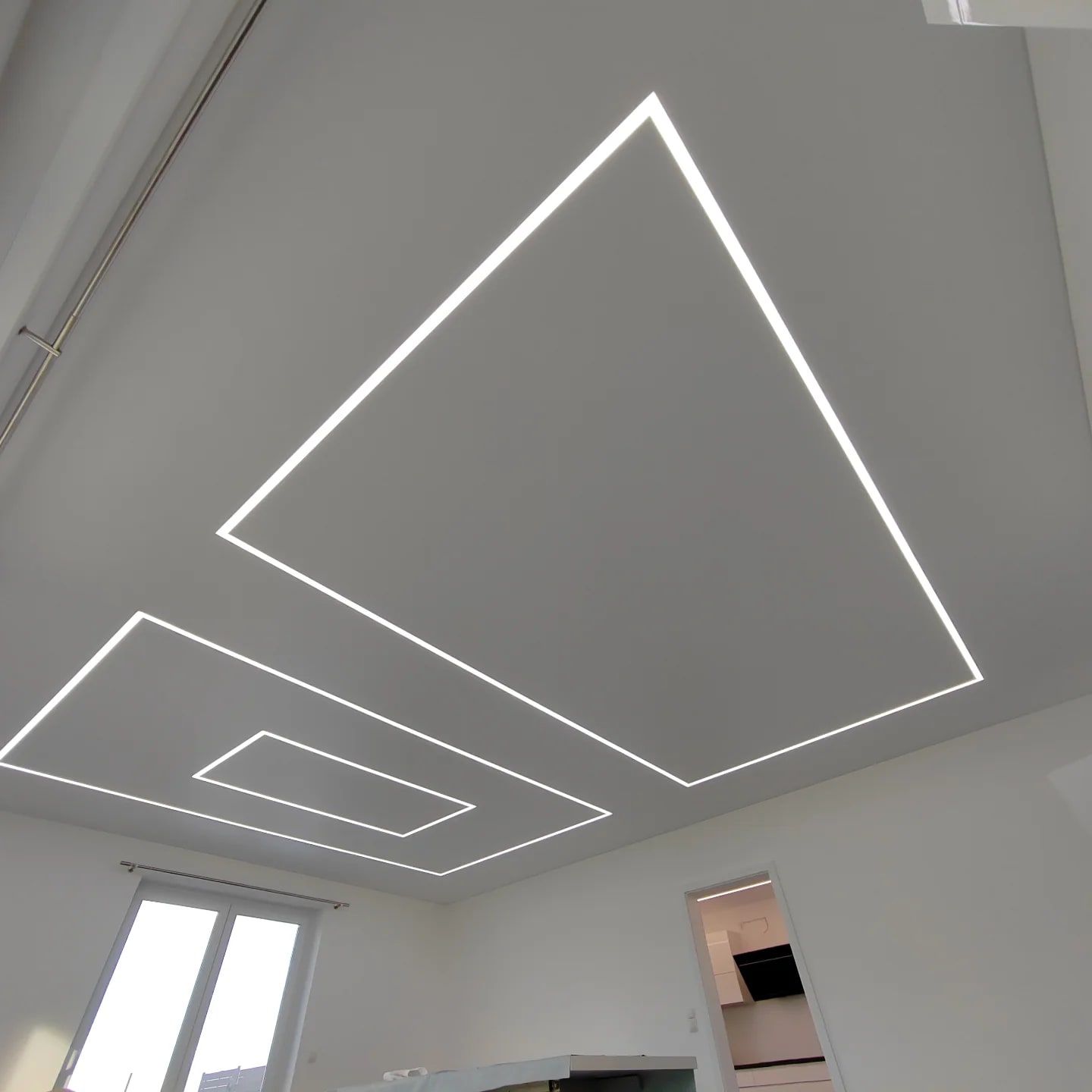 Weiße Decke mit mehreren geometrischen Lichtkonturen im Wohnzimmer