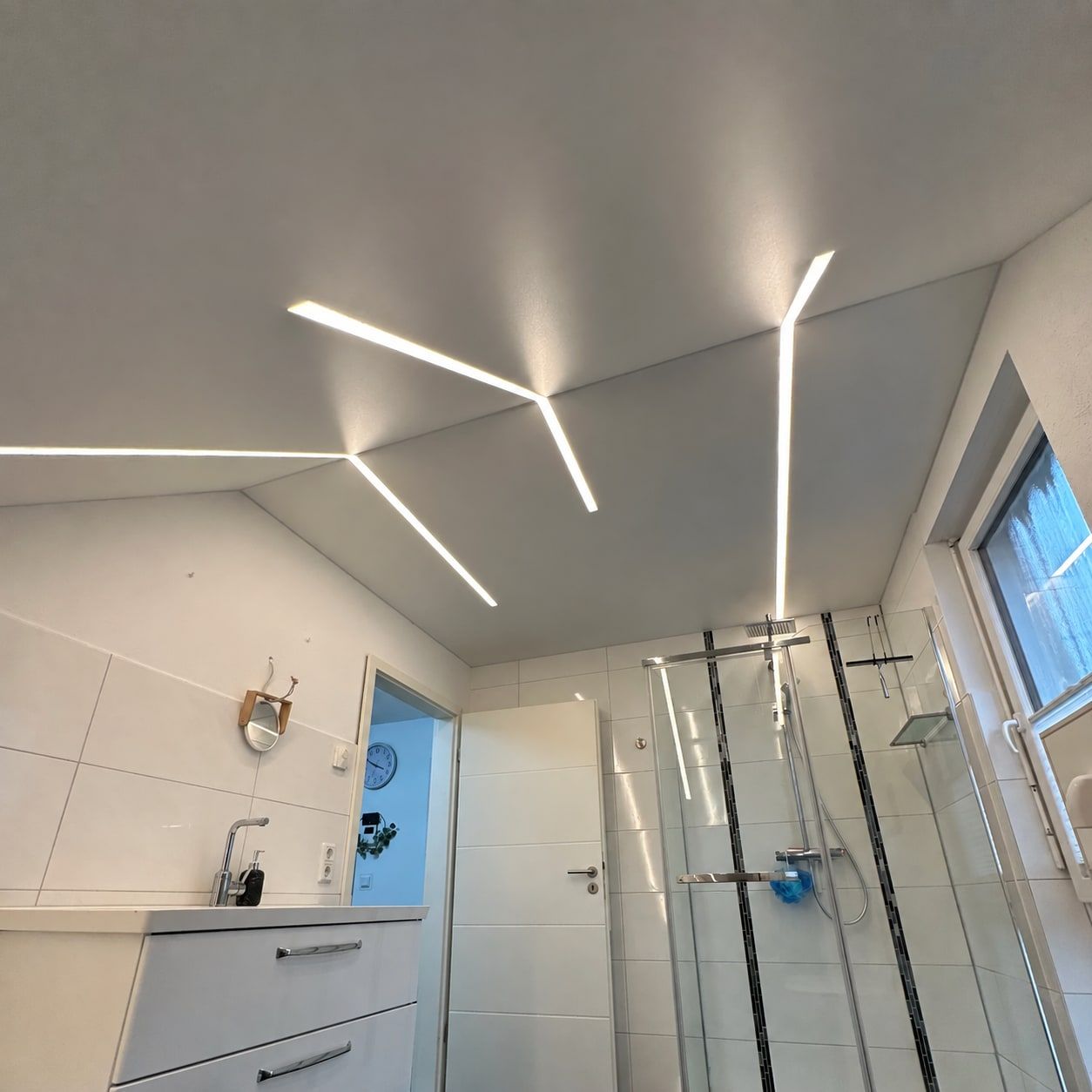 Badezimmer mit heller Spanndecke und verzweigten Lichtlinien